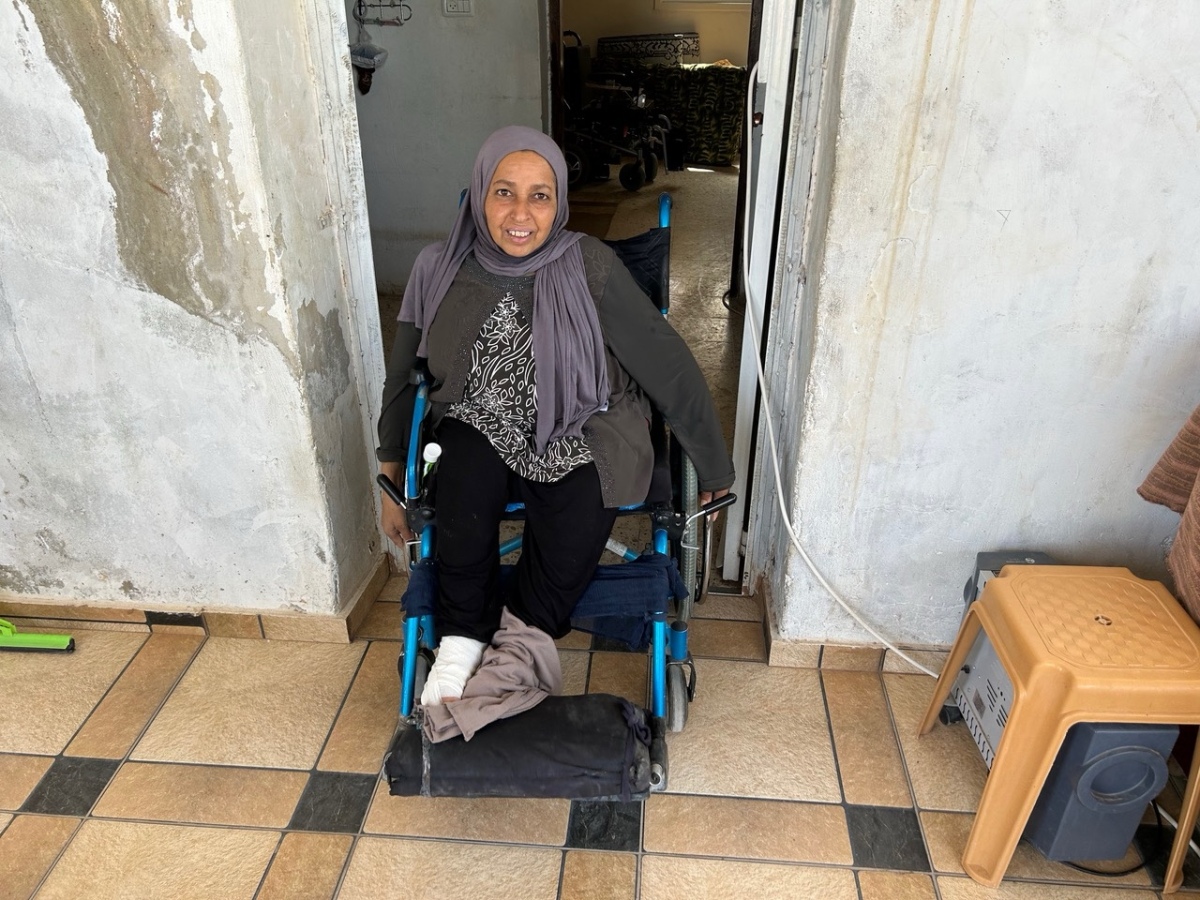 Eine Frau im Rollstuhl vor einem Hauseingang in Palästina